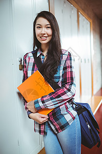 站在储物柜旁边的开心学生女士文件夹女性混血服装知识大学生休闲大学更衣室图片