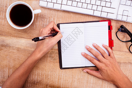在书桌上写日记的女商务人士裁剪职场杯子桌子饮料手指规划师木头眼镜电脑图片