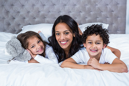 母亲在床上微笑 孩子在床上羽绒被女儿闹钟混血棉被家庭枕头卧室公寓快乐图片