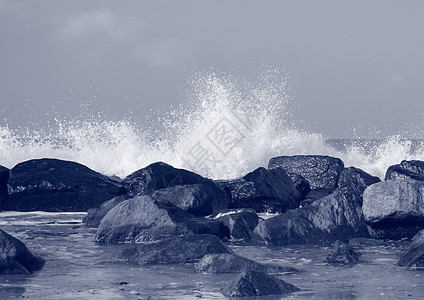 保护海岸免受白浪冲撞的黑岩石影响图片