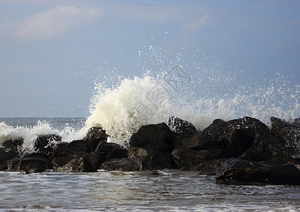 海岸对黑岩石的撞击波浪海浪蓝色天空激流液体盐水戏剧性海洋危险大自然图片