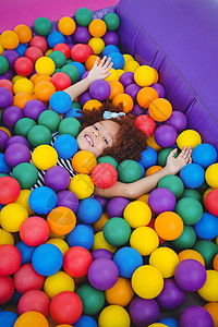 在海绵球池里笑笑的可爱女孩时间喜悦娱乐快乐享受水池游戏童年微笑娱乐性图片