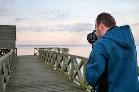 拍摄日落时湖景照片的自然摄影师技术男性游客行动男人成人爱好拍照自由职业者相机图片