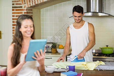 在厨房里熨衬衣情人电脑房子女士衬衫公寓男人技术沟通短信图片