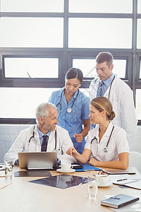 医疗队在会议室内互动的小组女士平板实习生电脑职业桌子微笑快乐诊所检查图片