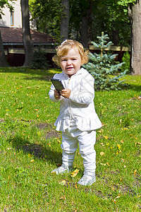 使用移动电话的可爱婴儿绿色女性电话女孩细胞新生白色公园孩子背景图片