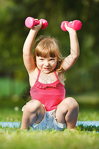 有哑铃的小女孩快乐力量俏皮活动训练生活方式重量童年小姑娘公园背景图片