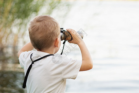 小男孩在河岸看望双筒望远镜情感机械游客微笑手表探险家男生眼镜码头童年伪装高清图片素材