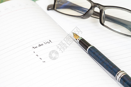 要在笔记本页面上用木头背景上的笔写列表清单项目战略程序教育笔记成功时间工作白色图片