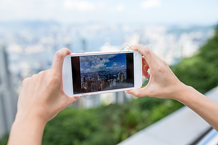 妇女用手机在香港市风景中拍摄照片图片