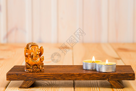 歌神加内沙的木制雕像和一支支持的蜡烛背景