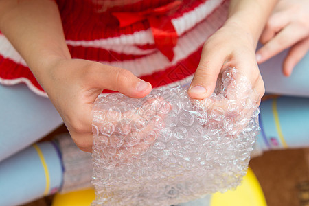 儿童双手的顶端视图 按下包装胶片上的泡泡图片