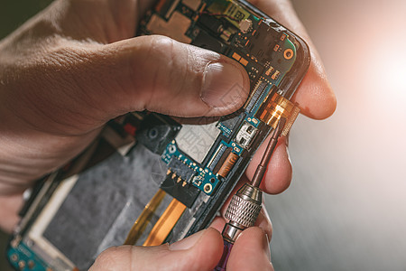 修理一部移动电话的人技术员焦点工具电子检查电路板男士螺丝刀服务手机图片