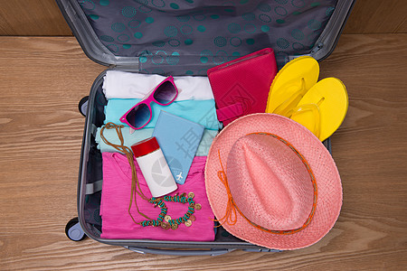 打开行李旅行和休假概念 开放旅行者带衣物的包袋钱包信用护照游客卡片桌子衣服电话相机配件背景