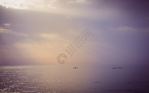 日落时有三艘独木舟在海上航行图片