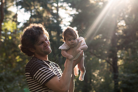 快乐快乐的父亲玩得开心 他的孩子在日落背景下抛向空中  故意的阳光眩光和复古色彩 镜头聚焦在父亲身上 父亲节 胶片滤镜蓝色婴儿乐图片