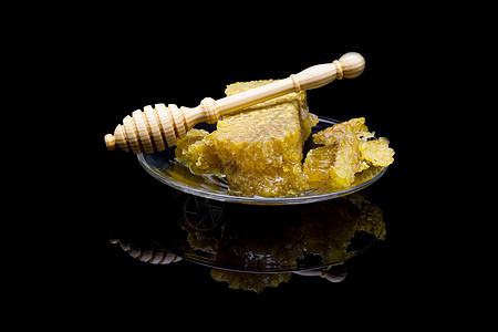 黑色背景中隔离的玻璃板上带有蜂窝的蜂蜜药品蜂蜡勺子甜点蜜蜂金子早餐玻璃木头食物图片