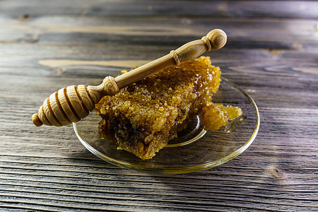 蜂蜜与蜂窝蜂蜜 在旧木制桌子上的玻璃盘子上液体厨房药品食物木头蜂蜡营养早餐金子健康图片