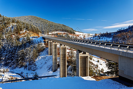 冬季的山桥 有雪和蓝天空农村路线基础设施蓝色晴天驾驶悬崖速度沥青汽车图片