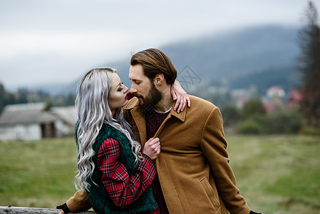 情侣拥抱喀尔巴阡山上的情侣外套拥抱成人前戏夫妻女士笼子栅栏热情红裙子背景
