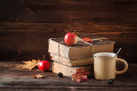 秋天的静物生活 有旧书 苹果枫叶和木制背景上的一杯咖啡图片
