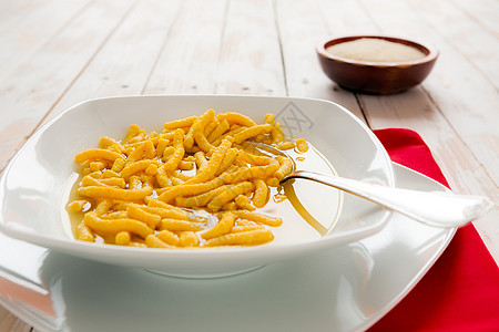 意大利薄汤的意大利皮卡图利木头盘子乡村餐巾水平食物勺子红色桌子白色图片