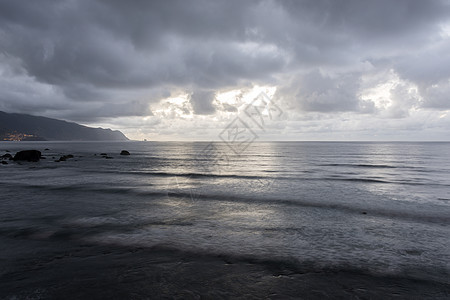 黑云笼罩着大海石头波浪村庄地平线天气海洋图片