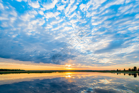 美丽的乌云笼罩在光辉的湖上 黎明时橙色太阳图片