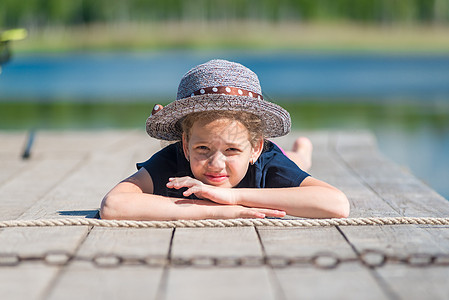 一个戴着帽子的女孩的肖像画 在湖边一个木头码头上人们高清图片素材