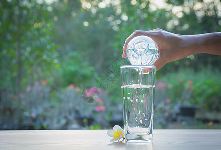 女性用手把水从瓶子倒到玻璃上塑料桌子苏打矿物生活液体运动白色女士蓝色图片