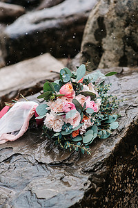 冬季婚礼带有石上丝带的彩色新婚花束玫瑰装饰树叶叶子植物乡村花朵丝带橙子石头背景