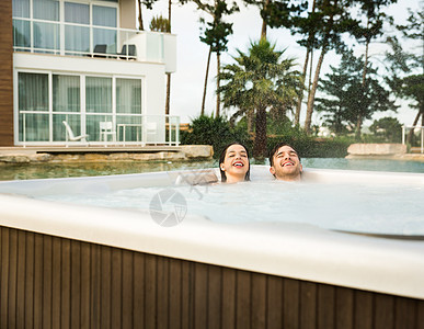在浴缸里的年轻夫妇温泉微笑男朋友女朋友女士水池假期漩涡按摩水疗图片