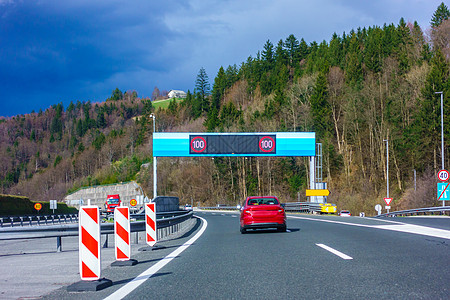 公路上现代LED的交通标志 红色汽车 道路上的卡车树木车辆街道技术驾驶丘陵农村山脉小路场景图片