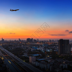 城市上空日落日出时在城市上空空中飞行的飞机休眠奢华速度假期商业航空航空公司建筑学翅膀客机空气背景