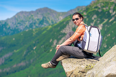 山里背着背包的远足女子坐在岩石上图片