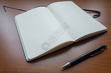 打开的笔记本白纸笔记本和棕色木制表背景的薄纸背景