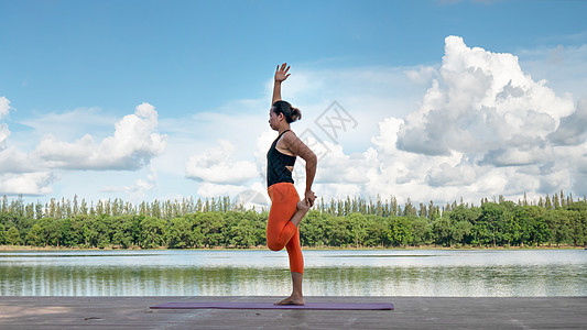 亚裔妇女练瑜伽姿势天空女性公园身体蓝色女孩专注运动平衡反射图片