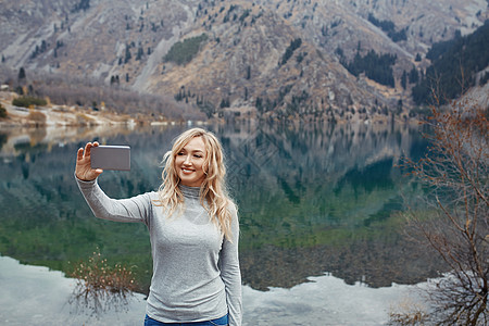 微笑的女人在山湖做自拍假期旅游娱乐女性冒险反射农村工具技术自然图片