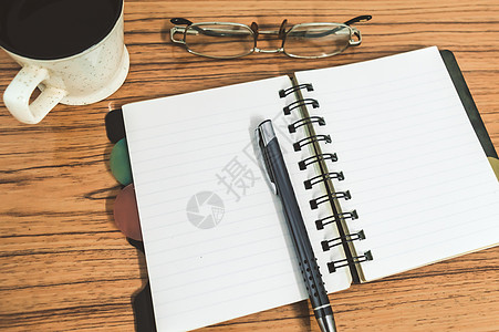 桌子上有打开的笔记本 上面有空白页 眼镜 笔和一杯咖啡 带复制空间的顶视图 商业静物概念与桌上的办公用品 教育 工作或规划概念活图片