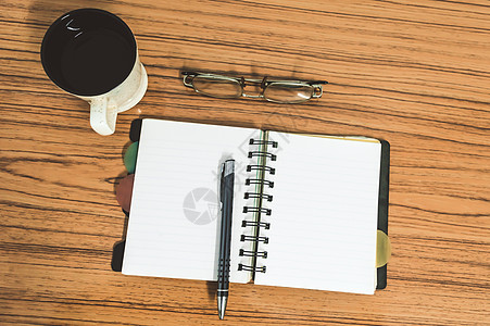 桌子上有打开的笔记本 上面有空白页 眼镜 笔和一杯咖啡 带复制空间的顶视图 商业静物概念与桌上的办公用品 教育 工作或规划概念事图片
