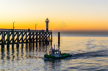比利时布兰肯堡港的小型轮船航行 底底有灯塔的码头 日落时天色多彩图片