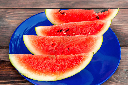 在木制桌子上的蓝色板块上 切成熟熟熟的红西瓜水果浆果食物甜点热带盘子饮食营养花园图片