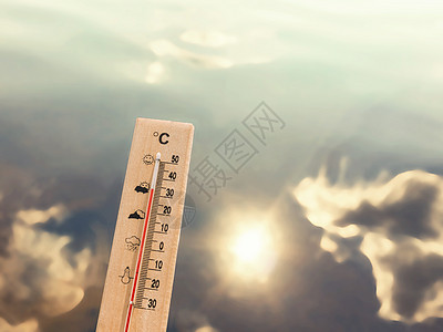 显示 30 度热量的温度计以湖水为背景 有云和太阳的反射背景图片