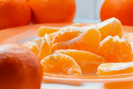 在橙色盘子上剥了几片整条熟熟的橘子果汁水果美食食物生物橘味小吃团体桌子热带图片