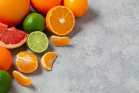 橘子片一组完整和切片的柑橘类水果 — 灰色桌子表面的橘子 柠檬 酸橙 橙子 葡萄柚 — 带有复制空间的图像背景