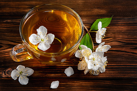 菲利亚德尔弗斯的花朵 在叫茉莉或假橙和杯子的地方 黑木桌上有香茉菊茶绿茶梅花饮料茶点植物玻璃桌子芳香香气照片图片