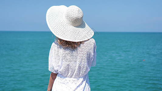 年轻女子站在海边沙滩上 戴着帽子比基尼阳光女士闲暇天空女性热带旅游姿势棕褐色图片