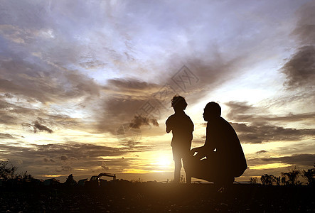 父亲和儿子的轮廓 他们享受日落为图片