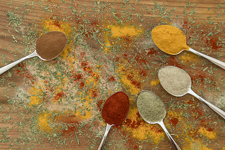 在勺子上安排各种彩色调味品香气种子辣椒草本植物味道木头香料烹饪金属粉末图片