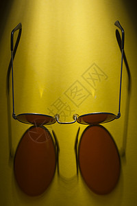 黄色表面的圆太阳镜桌子眼镜阴影镜片反射圆形潮人黑色框架图片